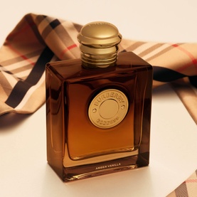 Burberry Goddess Amber Vanilla EDP in amber glass bottle with gold cap, Burberry check scarf in background
