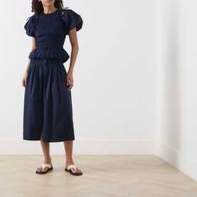 Model wearing Damson Madder Navy Blouse with matching navy midi skirt and white strappy flat sandals.