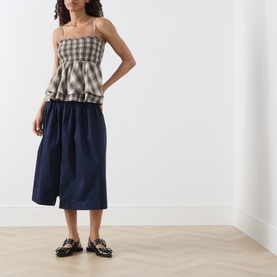 Model wearing Damson Madder Cardamon Check cotton cami top, styled with navy midi skirt and black loafer flats.