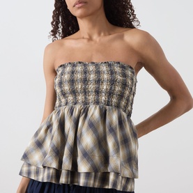 Model wearing Damson Madder cardamon check strapless cotton top with smocked bodice and tiered peplum hem, styled with navy skirt.