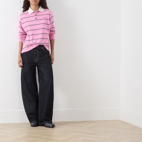 Model wearing Damson Madder pink stripe cotton polo top with white collar, styled with wide-leg black jeans and black loafers.