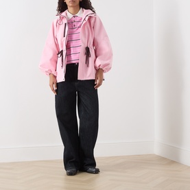 Model wearing Damson Madder pink stripe cotton top, styled with pink zip-up jacket and wide-leg black trousers.
