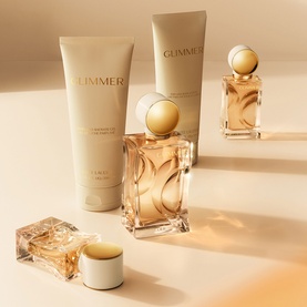Estee Lauder Glimmer collection in warm gold tones, featuring body lotion tubes, eau de parfum bottle, and miniature fragrance set.
