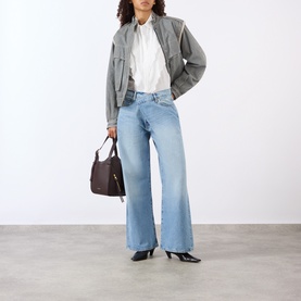 Model wearing FRAME DENIM Wide Leg Jeans in Dodger light blue wash, styled with grey bomber jacket, white shirt and black heels.
