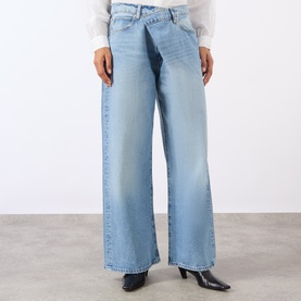 Model wearing Frame Denim Wide Leg jeans in Dodger light blue wash, styled with a white blouse and black ankle boots