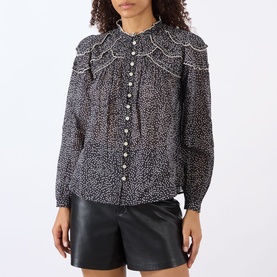 Model wearing Isabel Marant Etoile black and ecru cotton blouse with ruffle bib detail and button front, styled with black leather shorts.