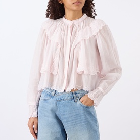 Model wearing Isabel Marant Etoile light pink cotton blouse with ruffle bib detail and long sleeves, styled with light blue denim jeans.