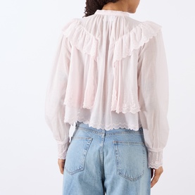 Model wearing Isabel Marant Etoile light pink cotton blouse with ruffle detail and lace hem, styled with light blue jeans. Back view.