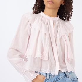 Model wearing Isabel Marant Etoile light pink cotton blouse with ruffle trim, scalloped hem and long sleeves, styled with denim jeans