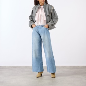Model wearing Isabel Marant Etoile light pink cotton top, styled with grey cropped jacket, wide-leg light wash jeans and tan ankle boots.