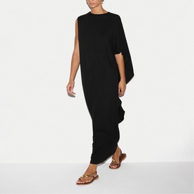 Model wearing Jigsaw black asymmetric cape maxi dress, styled with tan strappy flat sandals.