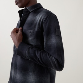 Model wearing Belstaff black cotton casual shirt with ombre check pattern, chest pocket, and logo badge on sleeve
