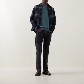 Model wearing Belstaff black checked cotton casual shirt, styled with teal sweatshirt, dark jeans and black leather shoes.