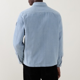 Model wearing Belstaff mist blue casual shirt, rear view, showing long sleeves with button cuffs and small arm badge detail.
