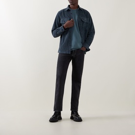 Model wearing Belstaff Petrol Crew Neck T-Shirt, styled with a dark overshirt, charcoal trousers and black leather boots.