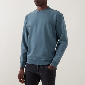 Model wearing Belstaff petrol cotton sweatshirt with crew neck, ribbed cuffs and hem, sleeve badge detail, paired with dark jeans