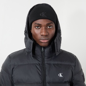 Model with Calvin Klein Monogram Logo Fine-Rib Beanie Hat in black, styled with a black puffer jacket with hood