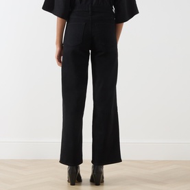 Model wearing FRAME DENIM Wide Leg Jeans in black, rear view, styled with a black top and black ankle boots.