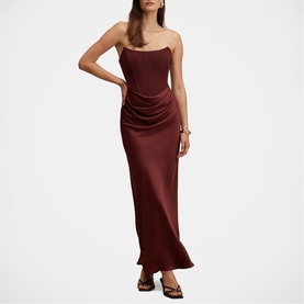 Model wearing Forever New strapless maxi dress in Vintage Burgundy satin, featuring ruched side detail and flared hem, styled with strappy heels
