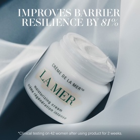 La Mer Cr&egrave;me de la Mer moisturising cream jar open, displayed on white silk fabric with barrier resilience claim text overlay.
