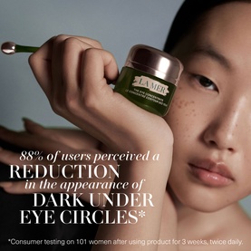 Model with La Mer Best Sellers Skincare Gift Set, holding a small dark green jar with rose gold lid near face