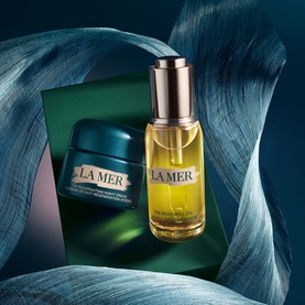 La Mer Rejuvenating Anti-Ageing Skincare Gift Set featuring a face oil bottle and moisturiser pot on a teal draped background