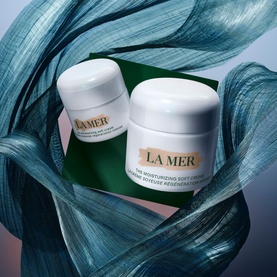 La Mer Moisturizing Soft Cream Hydration Gift Set featuring two white cream jar sizes on a green card with teal fabric backdrop