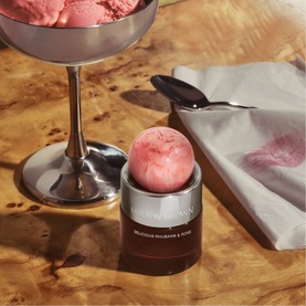 Molton Brown Delicious Rhubarb & Rose Eau de Parfum 30ml styled with pink ice cream scoops and a napkin on a marble surface.