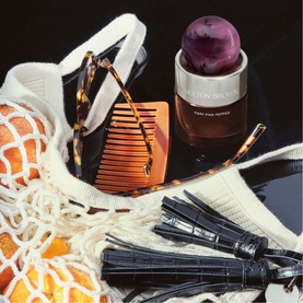 Molton Brown Fiery Pink Pepper Eau de Parfum 30ml styled with tortoiseshell comb, sunglasses, black tassel keyring and mesh bag
