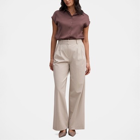 Model wearing Forever New Chocolate Brownie short sleeve button-up shirt, styled with wide-leg stone trousers.