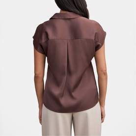 Model wearing Forever New Chocolate Brownie short-sleeve satin blouse, back view with centre pleat detail, styled with cream trousers.