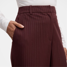 Model wearing Forever New berry pinstripe wide-leg trousers, high-waist with side pocket, styled with a white long-sleeve top.