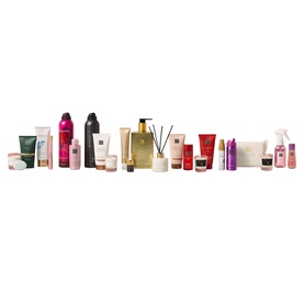 Rituals Premium Advent Calendar displayed on a table in a festive train carriage setting, with multiple beauty products arranged around the red gift