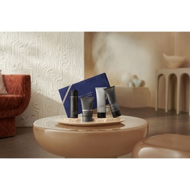 Rituals Homme Small Gift Set displayed on a round table, featuring miniature grooming products and a blue pouch in a styled interior setting.