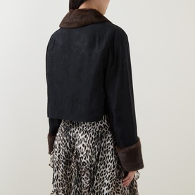 Model wearing Rixo London black viscose jacket, rear view, with dark faux fur collar and cuffs, styled with leopard print skirt.