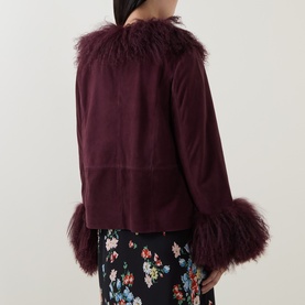 Model wearing Rixo London maroon lamb suede jacket with fluffy shearling collar and cuff trim, back view, styled with floral skirt.