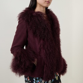 Model wearing Rixo London maroon lamb suede jacket with tonal fluffy shearling trim, styled with floral trousers.