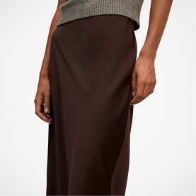 Model wearing Forever New chocolate satin midi skirt, styled with a grey knit top.