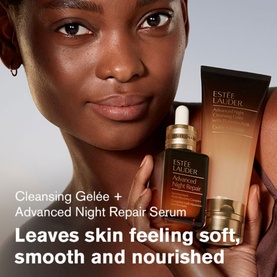 Model with Est&eacute;e Lauder Advanced Night Repair Skincare Gift Set, holding serum and cleanser products against glowing skin.