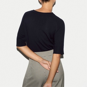 Model wearing Jigsaw navy elbow-sleeve top, styled with a grey houndstooth mini skirt, back view.