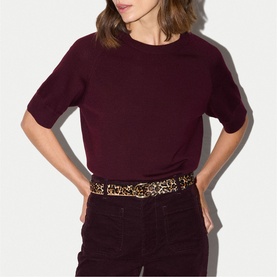 Model wearing Jigsaw burgundy short-sleeve crew neck top, styled with matching burgundy trousers and leopard print belt.