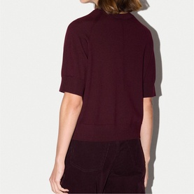 Model wearing Jigsaw burgundy short-sleeve fine knit top, back view, styled with burgundy wide-leg trousers.