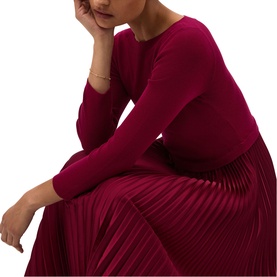Model wearing Hobbs calla pink long-sleeve dress with pleated midi skirt, seated pose