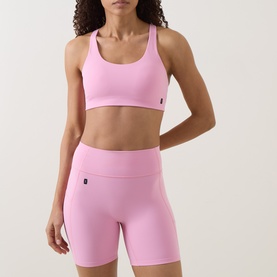 Model wearing On Running Bras in Magnolia pink, styled with matching pink cycling shorts
