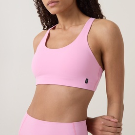 Model wearing On Running Bra in Magnolia pink, with matching high-waist leggings. Scoop neckline, cross-back straps.