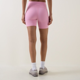 Model wearing On Running Shorts in Magnolia pink, high-waisted seamless bike short style, styled with white socks and grey trainers.