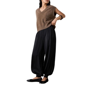 Model wearing Whistles black wide-leg tapered trousers with a tan knit vest top and black flat shoes.
