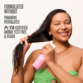 Model holding Sol De Janeiro Leave-In Conditioner spray, running it through long hair. PETA-certified, vegan formula text overlay visible.