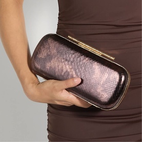 Model carrying a bronze metallic snake-embossed hard clutch bag with gold-tone frame clasp closure