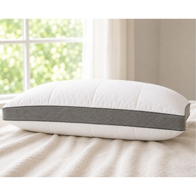 The Soft Bedding Co pillow in white with grey textured border band, shown on a bed in a bright room.